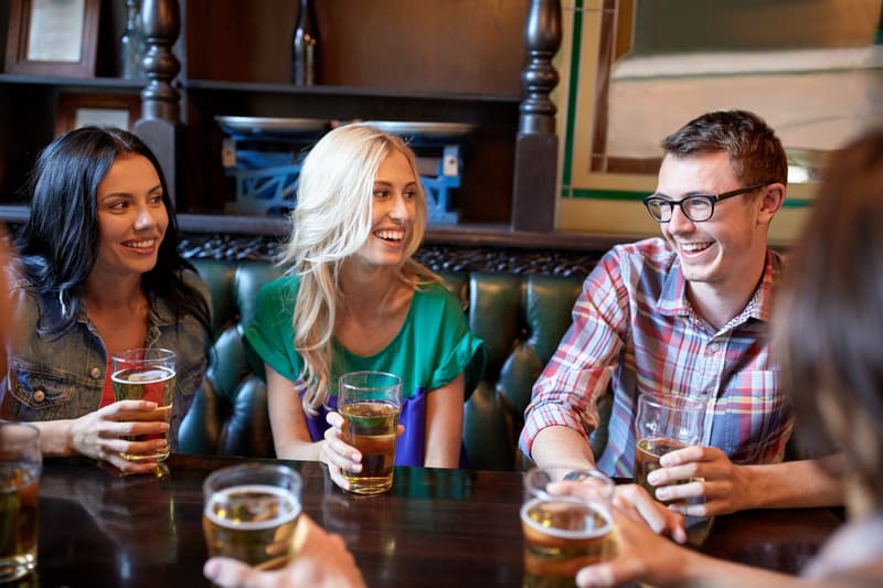 Amigos riéndose y charlando con unas cervezas en la mesa de un pub